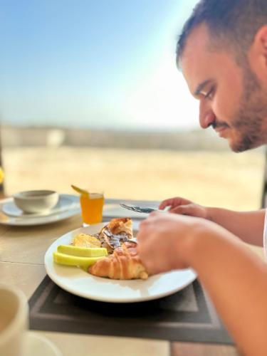 a man sitting at a table with a plate of food at Daniela Diving Resort Dahab in Dahab