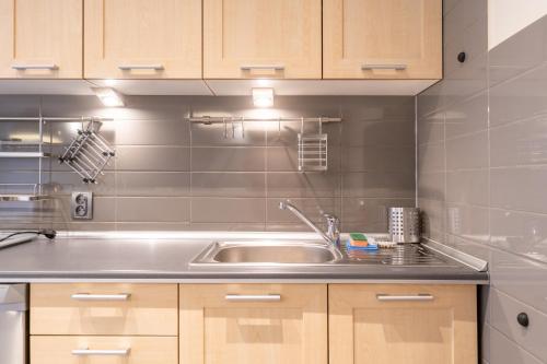 a kitchen with a sink and wooden cabinets at Katowice Central Apartment by BookingHost in Katowice