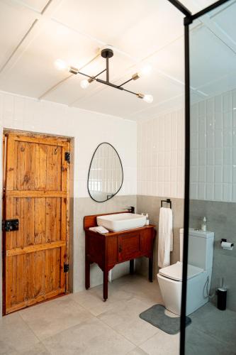 a bathroom with a wooden door and a toilet and a sink at Cottage at 48 in Graaff-Reinet
