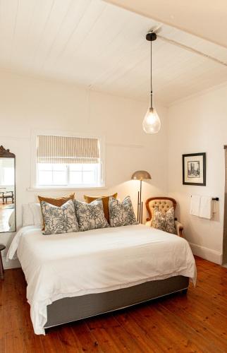 a bedroom with a large white bed with pillows at Cottage at 48 in Graaff-Reinet