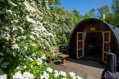 a building with a wooden deck with a bench and flowers at Green Oak Nature Retreat in Dunfermline