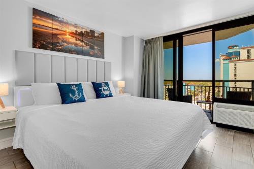 a white bedroom with a large bed and a balcony at Gorgeous 1BR Oceanview Suite, Dogs OK 904 in Myrtle Beach