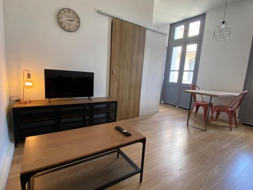 a living room with a tv and a table at V2 Studio avec balcon, plein centre - 5 min Golfech in Valence-dʼAgen