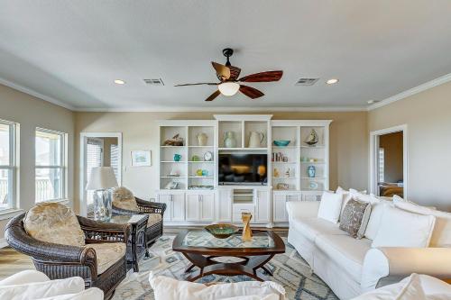 een woonkamer met een witte bank en een plafondventilator bij CoCo Beach in Crystal Beach