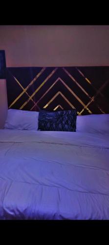 a bed with white sheets and a wooden head board at Abasis apartment in Abeokuta
