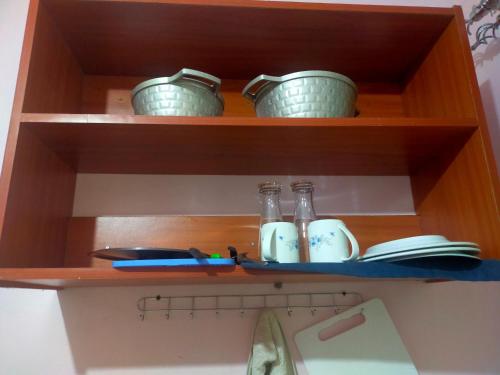 a shelf with three glass bottles and a book at Mini farmhouse in Kakamega
