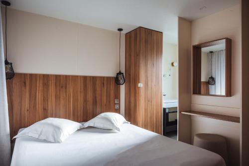 Un dormitorio con una cama blanca y un espejo. en Nova Lodges, en Grimaud