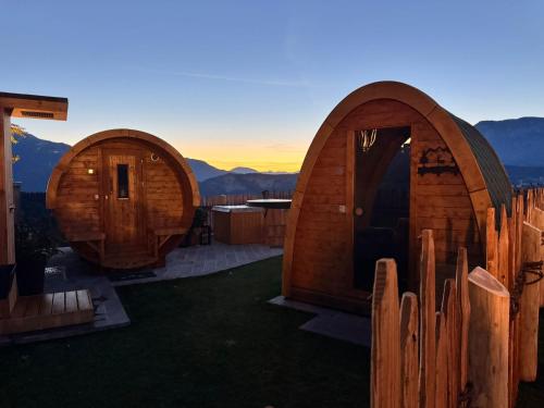 two circular wooden cabins with mountains in the background at Agritur Maso Librar in Trento