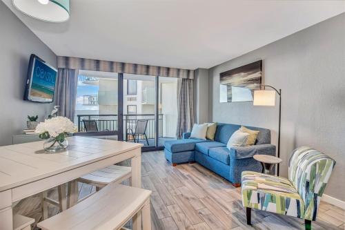 a living room with a blue couch and a table at Note worthy 1BR Oceanview Dogs OK! 438 in Myrtle Beach