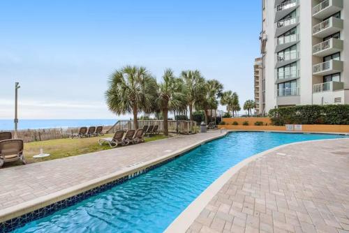 a swimming pool with chairs next to a building at Note worthy 1BR Oceanview Dogs OK! 438 in Myrtle Beach