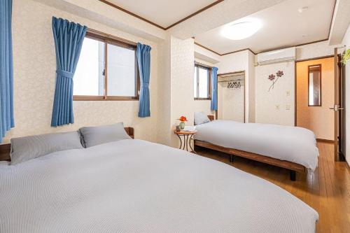 two beds in a room with blue curtains at 台東区広々吹き抜けリビングのメゾネットタイプのお家 in Tokyo