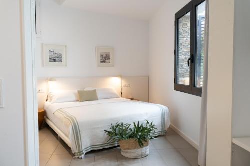 a bedroom with a white bed with a potted plant at Gaia Apartments & Lofts Cadaqués in Cadaqués