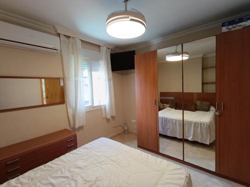 ein Schlafzimmer mit einem Bett und einem großen Spiegel in der Unterkunft Bonito apartamento en Rincón de la Victoria Playa a 100 metros in Rincón de la Victoria