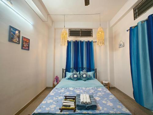 1 dormitorio con cama azul y cortinas azules en Hestia by Ghorsirika, en Guwahati