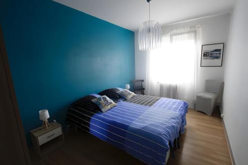 奥雷龙圣皮耶尔Appartement À Saint-Pierre-d'Oléron的一间蓝色的卧室，有一张床和一面蓝色的墙