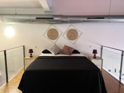 a bedroom with a large bed with black sheets and pillows at La Morada in Alcalá de Henares