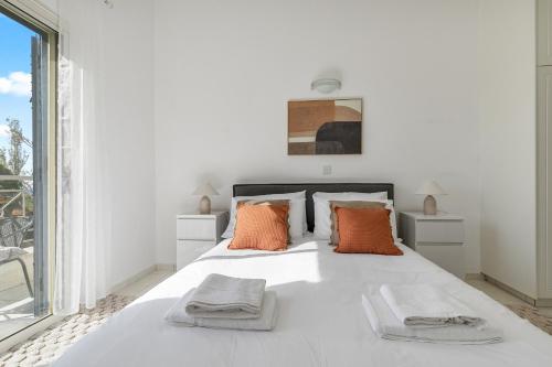 a white bedroom with a large white bed with orange pillows at Kastalia Springs 3bd VIilla in Peiya by VICHY Holidays in Paphos
