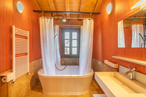 uma casa de banho com uma banheira, uma janela e um lavatório. em Espectacular casa con piscina próxima a Pamplona em Zizur Mayor