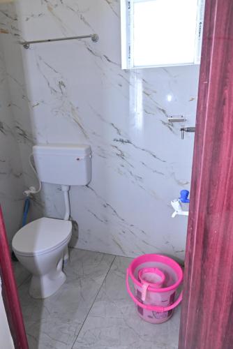 a bathroom with a toilet and a pink bucket at Gugan home stay in Tiruchchendūr
