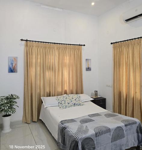 a bedroom with a bed and a window with curtains at Thiruthi Homestay in Vallikunnu