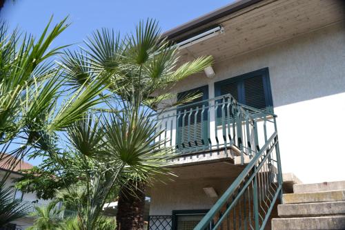 a balcony of a house with palm trees in front of it at Blue Coast Sicily in Fondachello