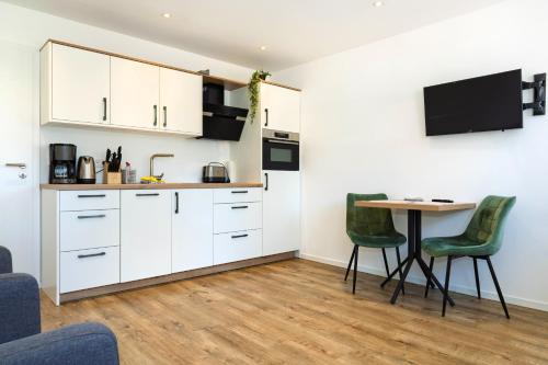 eine Küche mit weißen Schränken und einem Tisch und Stühlen in der Unterkunft Klosterhof Aue W 5 in Bad Zwischenahn