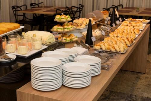 a buffet with white plates and food on a table at Go Inn Taguatinga in Taguatinga