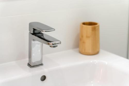 een badkamerwastafel met een kraan en een houten beker bij CASINHA Do FAROL in Praia do Carvoeiro