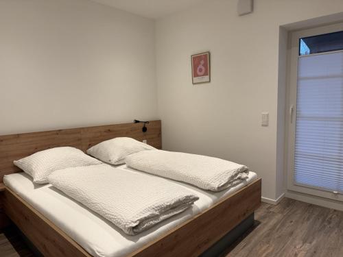 ein Schlafzimmer mit einem Bett mit weißen Laken und einem Fenster in der Unterkunft Klosterhof Aue W 14 in Bad Zwischenahn