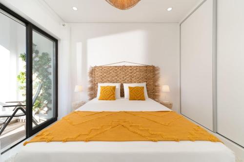 een slaapkamer met een groot bed met gele kussens bij CASINHA Do FAROL in Praia do Carvoeiro