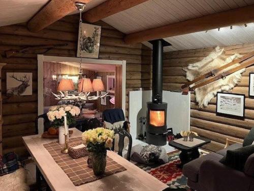 a living room with a table and a stove at Timber Cabin With Wood-Fired Hot Tub In Trysil in Granåsen