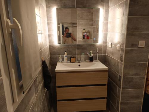 una mujer tomando una foto de un baño con lavabo en loue 2 chambres individuellemet chez l hote, en Pia