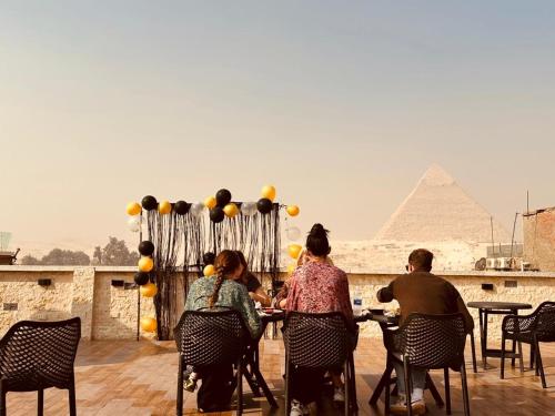 a group of people sitting at a table in front of the pyramids at Giza Pyramids Inn in Cairo