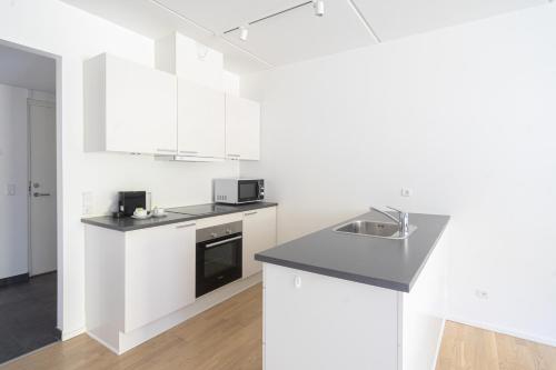Una cocina blanca con fregadero y encimera. en Spacious 2-BR w a balcony by Odense harbour - 93, en Odense
