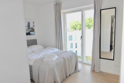 Un dormitorio blanco con una cama y una ventana grande. en Beautiful 1-BR w a balcony by Odense Harbour - 121, en Odense