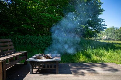 a picnic table with smoke on it next to a bench at Green Oak Nature Retreat in Dunfermline