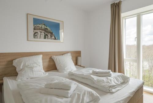 ein weißes Bett mit weißer Bettwäsche und Handtüchern darauf in der Unterkunft Beautful 2-BR in DGBN Silver property - 315 in Hunderup