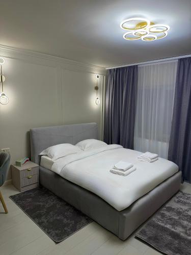 a bedroom with a large bed and a chandelier at Golden Sky Residence in Satu Mare