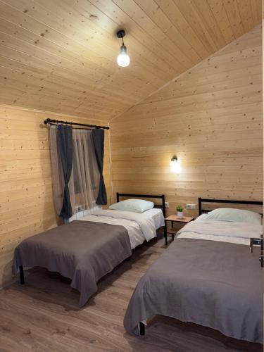 Dos camas en una habitación con paredes de madera. en Guest house in RIVERSIDE, en Haghartsin