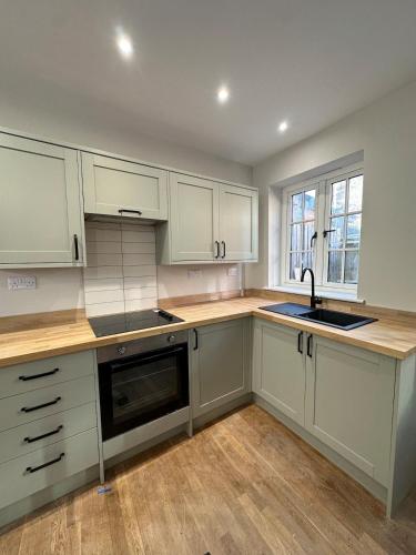 a kitchen with white cabinets and a sink at Cosy two bedroom cottage in Castle Donington