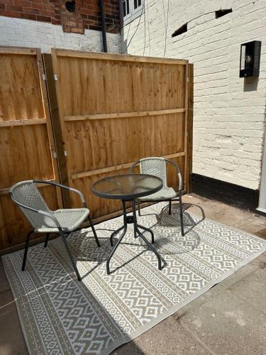 a table and two chairs on a rug next to a fence at Cosy two bedroom cottage in Castle Donington
