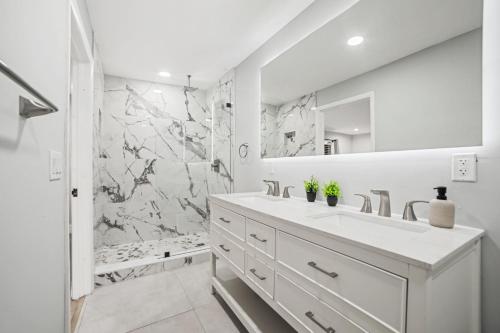 a white bathroom with a shower and a sink at Spacious 6BR Beach Getaway w Heated Pool in Barwal