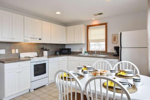 a kitchen with white cabinets and a table and chairs at 12215 - Beautiful Views of Cape Cod Bay Access to Private Beach Easy Access to P-Town in Truro