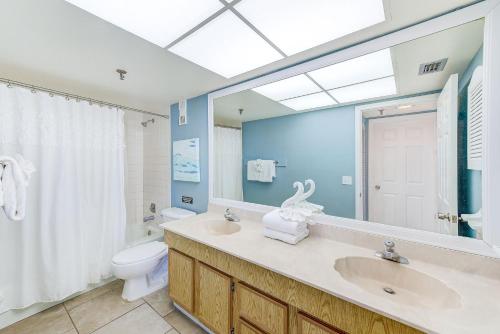 Un baño con lavabo, inodoro y espejo. en Beachfront Condo Sleeps 10 Heated Pool - 307, en St Pete Beach