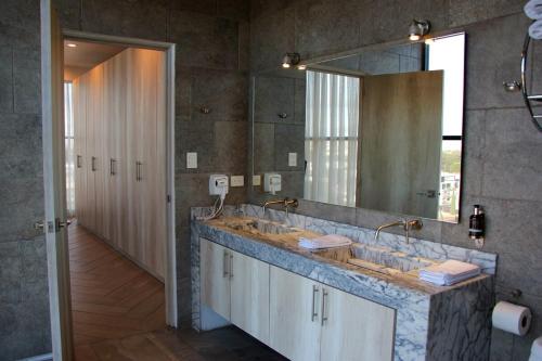 a bathroom with two sinks and a large mirror at Penthouse with Glass Floor and Volcano View in Cholula
