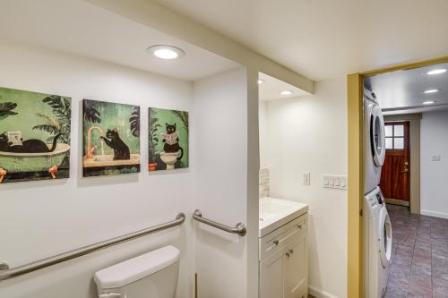 a white bathroom with paintings on the wall at Walk to Athens Riverfront Park! Modern-Retro Apt in Athens