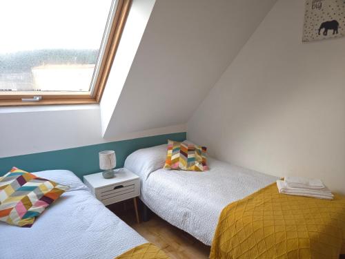 two twin beds in a room with a window at Ático Formoso in Cee