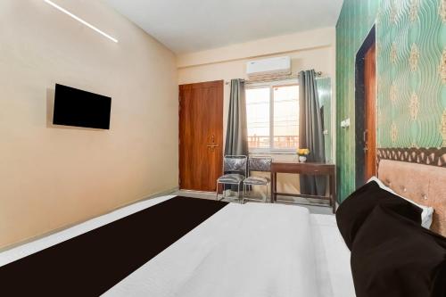 Habitación con cama, TV y escritorio. en Hotel O by OYO Swastik inn, en Gwalior