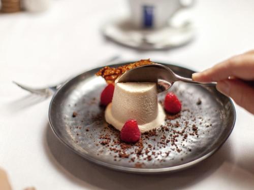 波高尔宾Mercure Hunter Valley Gardens的吃带勺子盘子上的甜点的人