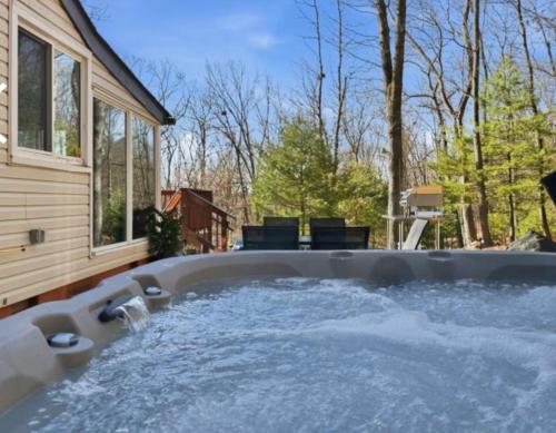 a jacuzzi tub in the backyard of a house at Pocono cabin with hot tub and private pool at Shawnee Mtn in East Stroudsburg